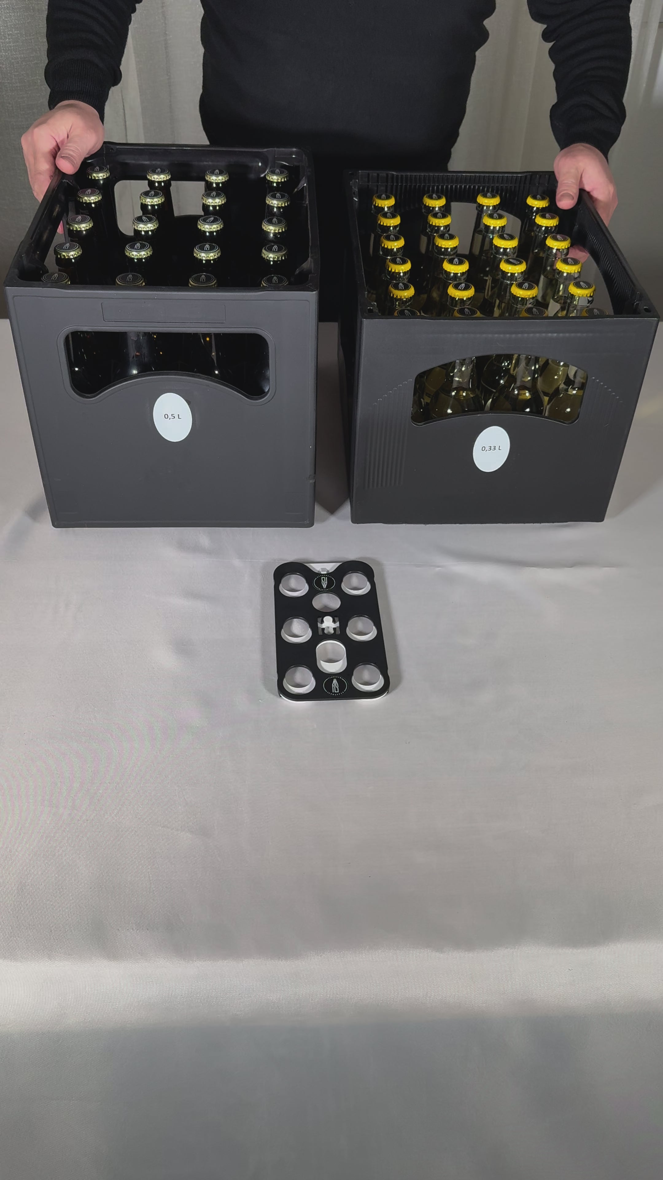 Video laden: Der Flaschen-Schnapper®, besteht aus zwei zusammengesetzten Teilen, welche parallel zueinander verschiebbar sind. Durch das Verschieben der beiden Platten entstehen zwei verschiedene Stellungen. Eine geöffnete Stellung, um den Flaschen-Schnapper® auf bis zu sechs Flaschen aufzusetzen. Eine geschlossene Stellung, die die Flaschen am Flaschenhals fixiert und zum Transport sichert. Das System wird über die beiden Trageöffnungen transportiert.